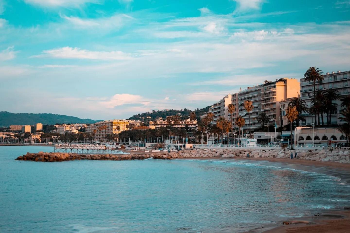 La plage et la Croisette à Cannes, vues depuis le bord de mer, avec les palmiers et les immeubles du front de mer. — Antibes · Juan-les-Pins