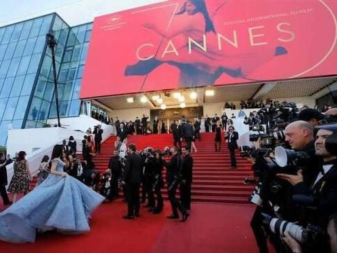 Le tapis rouge et les marches du Palais des Festivals à Cannes, sous l’affiche du festival, entourés de photographes. — Antibes · Juan-les-Pins