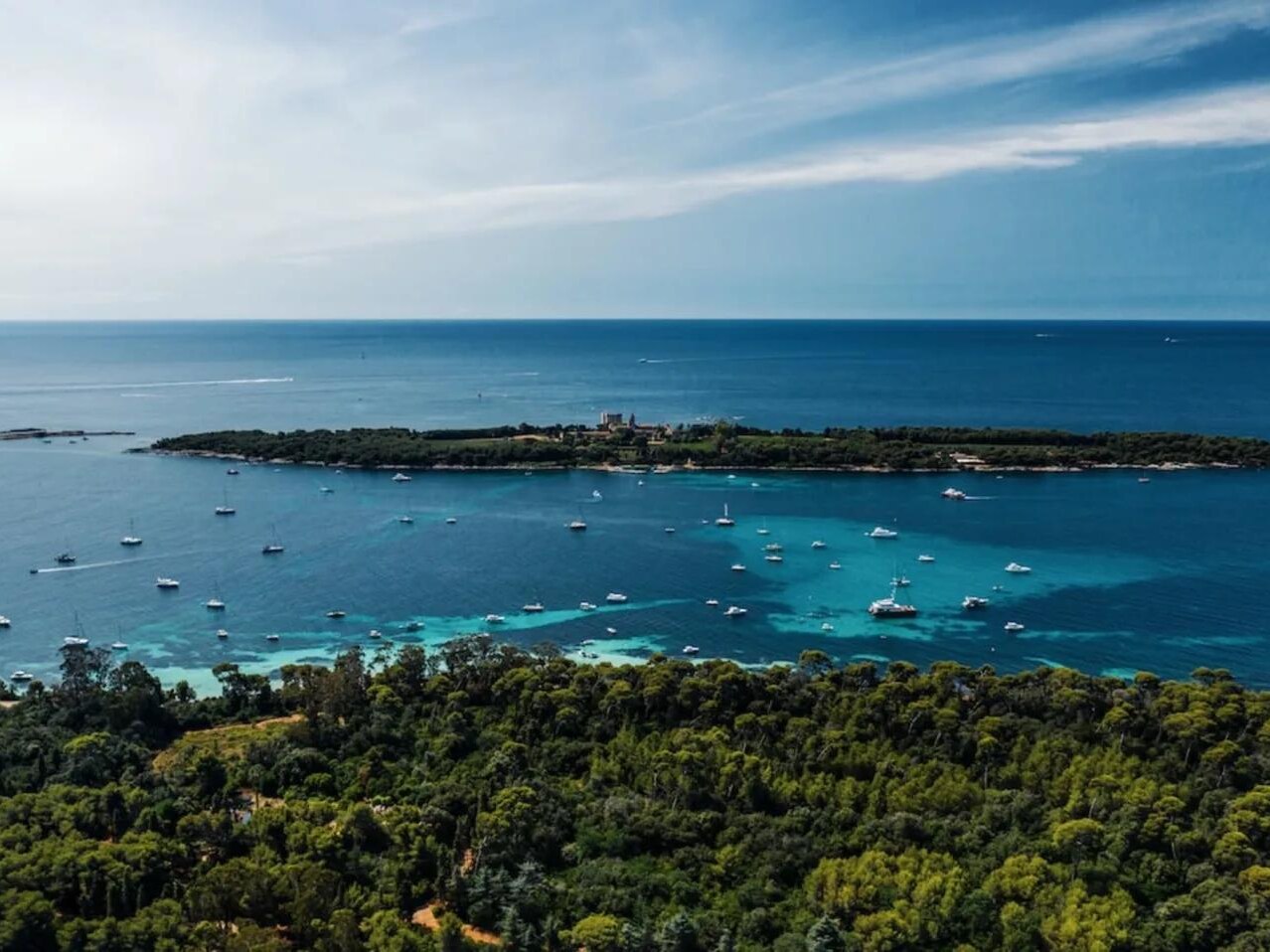 Les îles de Lérins vues d’avion : la pinède au premier plan, l’eau turquoise et les bateaux au mouillage entre les deux îles. — Antibes · Juan-les-Pins