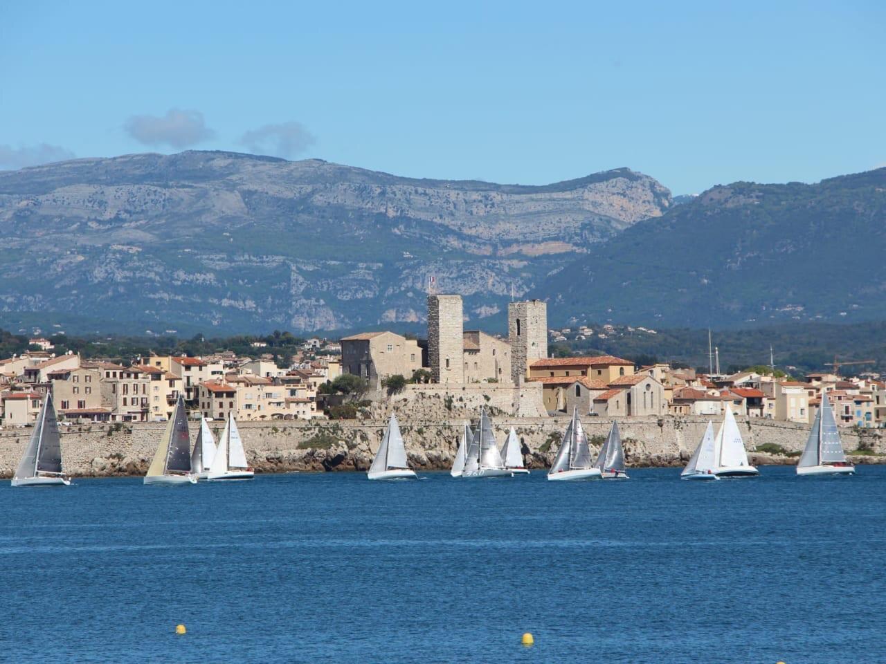 Les remparts du Vieil Antibes, le château Grimaldi et les toits de la vieille ville, devant une régate de voiliers. — Antibes · Juan-les-Pins